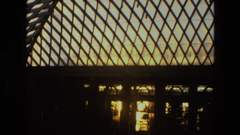 1972 Iran 8mm frame showing a diamond-lattice glass roof, dark arched windows, and warm light reflecting through the structure.