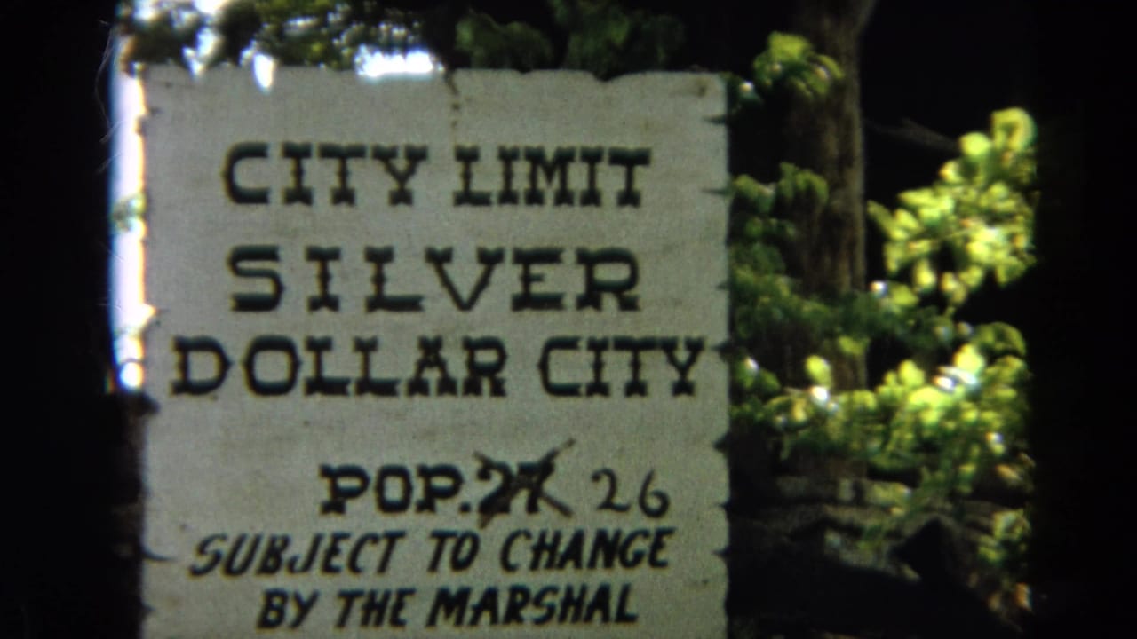 Weathered Silver Dollar City city limit sign with population note and foliage behind it.