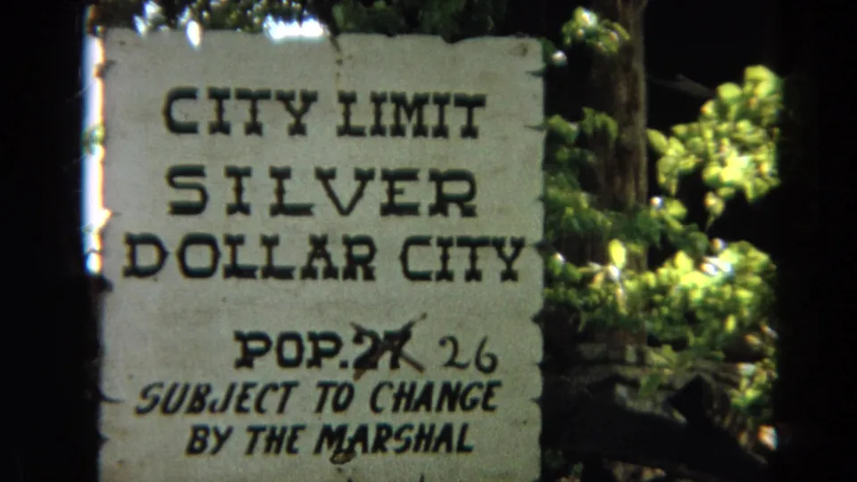 Final 8mm frame of the Silver Dollar City city limit sign near Branson, Missouri, with foliage and frame-edge darkness.