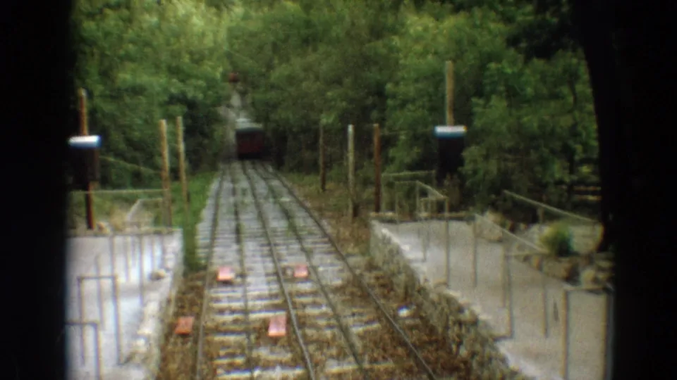 A red incline railway car nears the foreground landing in this 1968 Branson 8mm frame, with rails and woodland surrounding it.