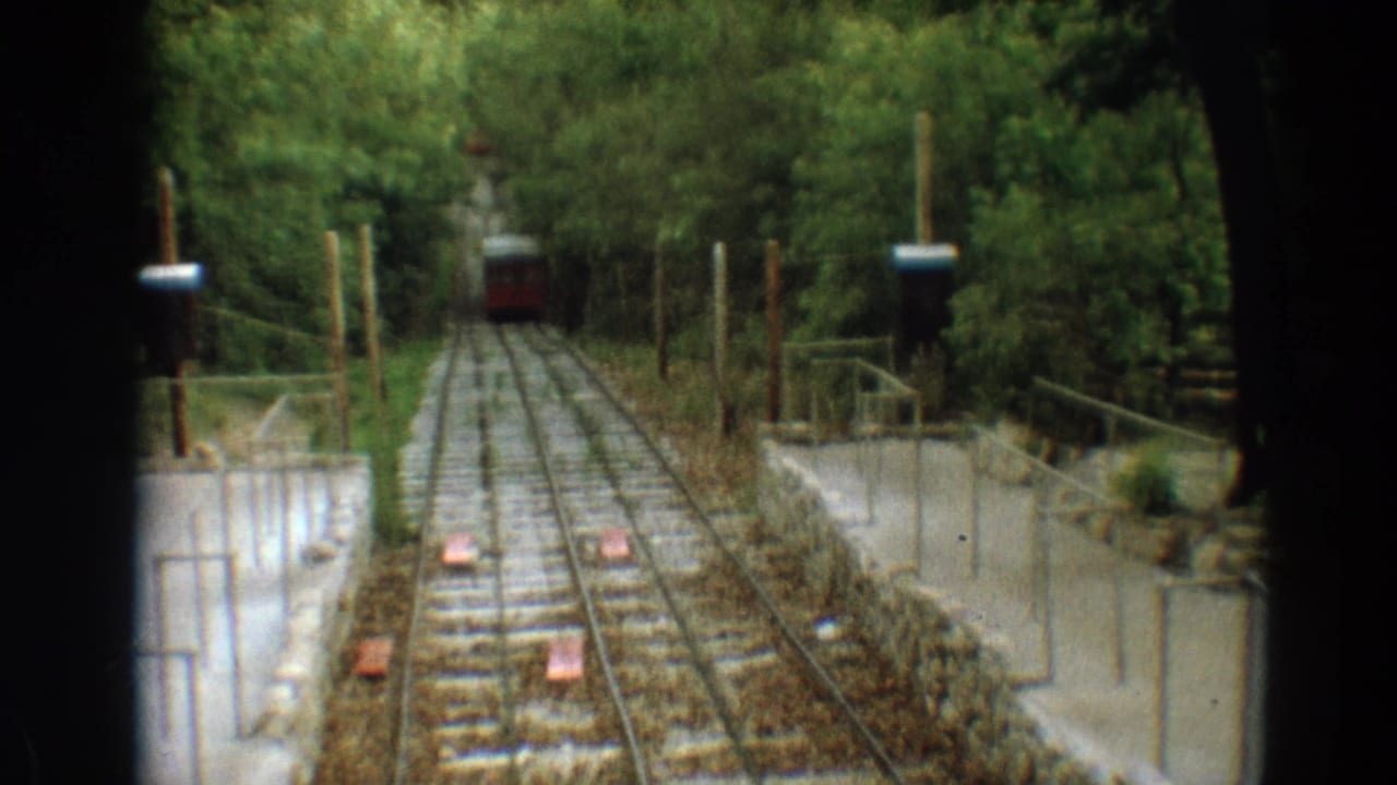 1968 Branson 8mm frame showing a red rail car in the distance on a steep wooded incline railway.