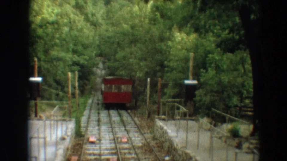 The red Branson incline rail car approaches the camera along wooden ties and metal rails in 1968 home-movie footage.