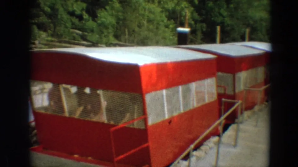 Close 1968 Branson frame showing the side and roof of the red trolley as it passes near the camera on the rail line.