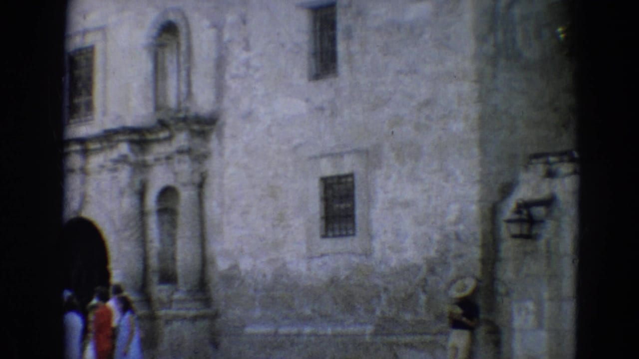 Visitors approach an arched doorway on a weathered stone facade.