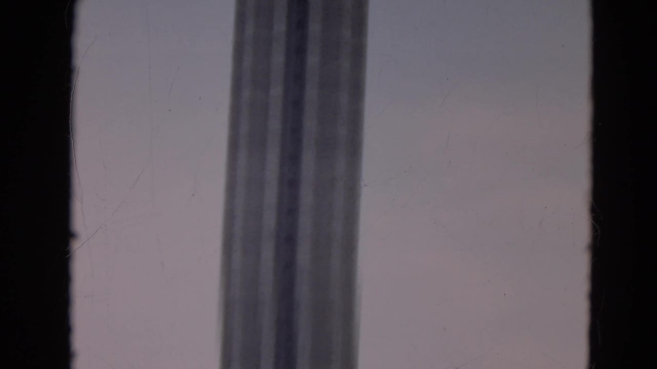 Dark window frame with a tall windowed structure against a pale sky.