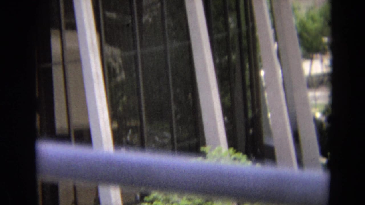 Glass building seen through dark foreground bars and a horizontal rail.
