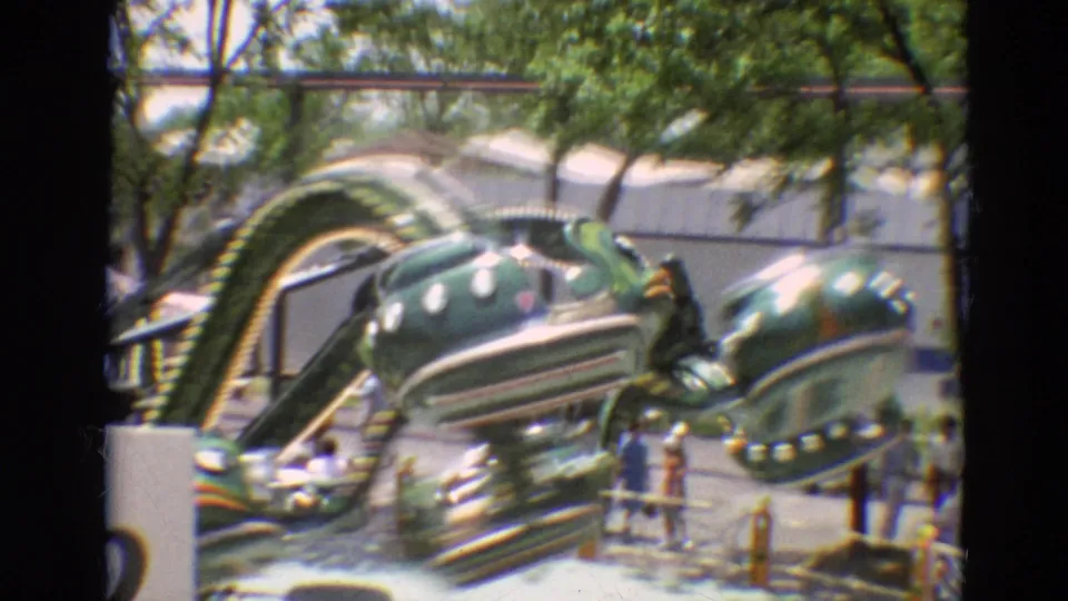 Green painted amusement ride appears beside trees and visitors in the 1968 Branson footage.