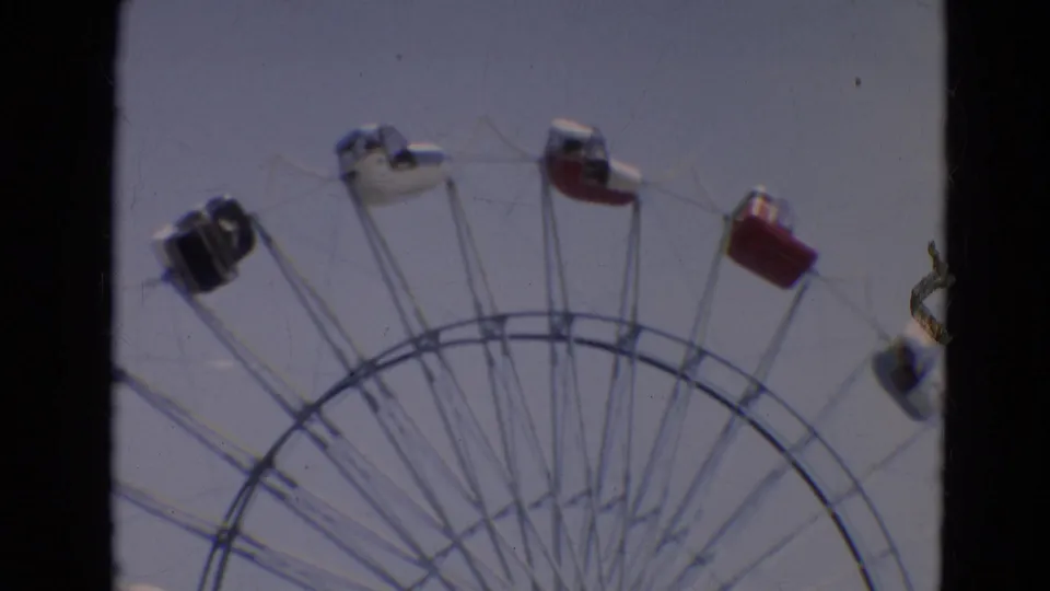 Soft 8mm view of a Ferris wheel in Branson, Missouri, with red, white and dark gondolas near the upper arc.