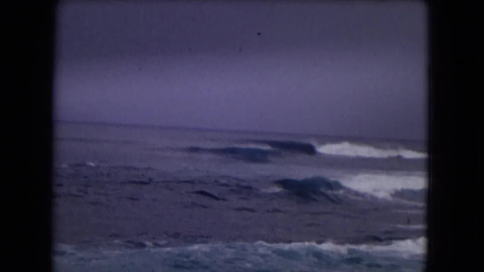 1968 Honolulu shoreline footage shows white surf breaking across dark blue water in soft 8mm focus.