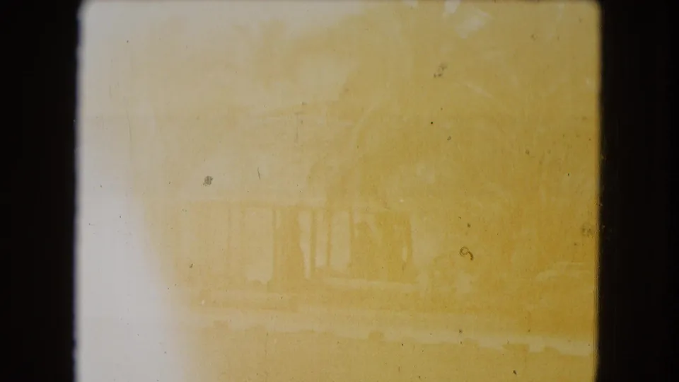 Overexposed 1968 Honolulu home-movie frame where the hut, palms, lawn, and shoreline are faintly visible.