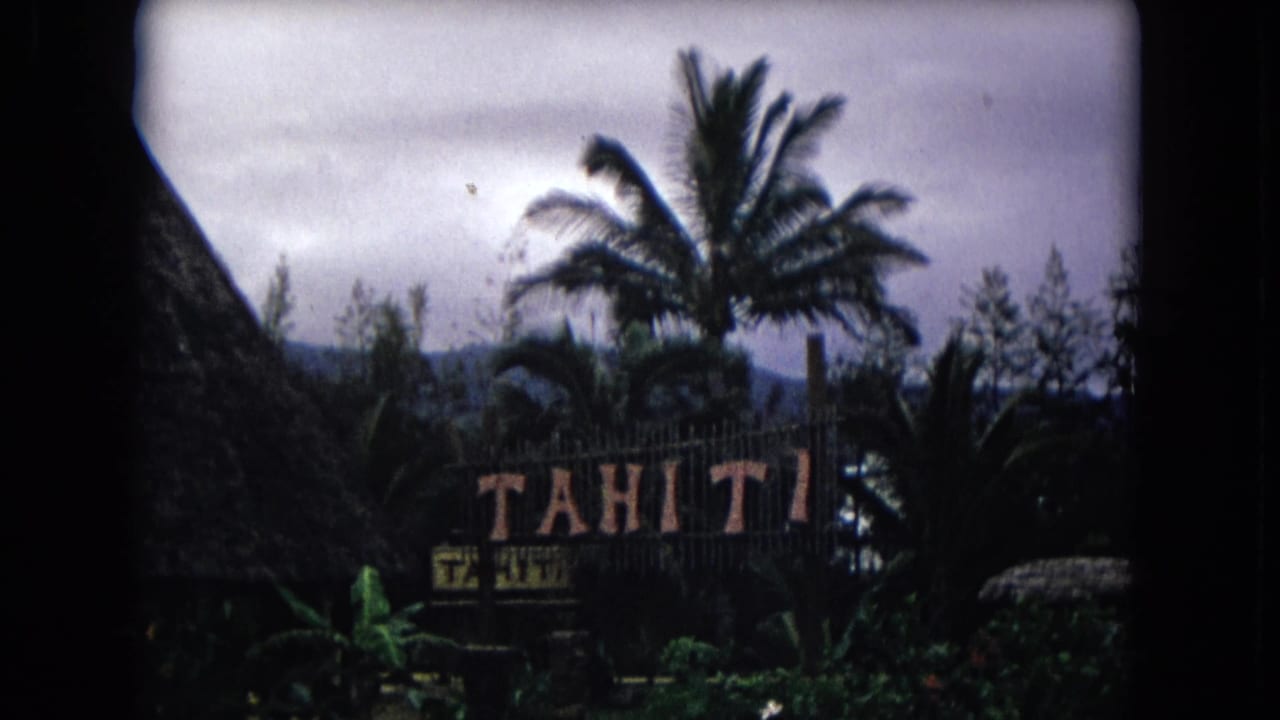 Thatched hut edge, Tahiti sign, palms, and tropical foliage under cloudy sky.
