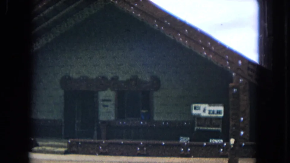 1968 Honolulu frame of the meeting-house exterior, showing carved roof trim, the entrance area, and a New Zealand sign on the right.