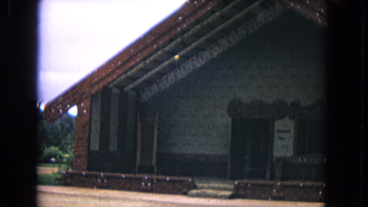 Low-angle view of a dark gabled building with carved trim and an entrance.