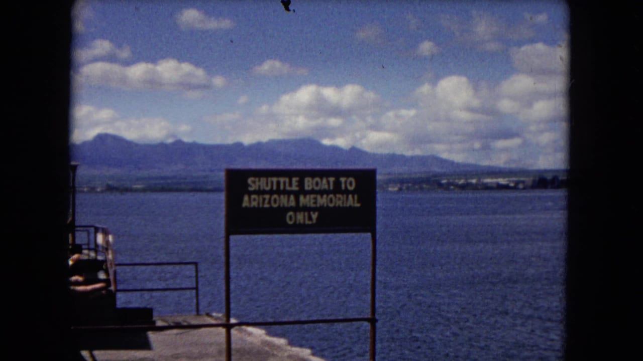 Brown shuttle boat sign beside harbor water with mountains and clouds behind it.