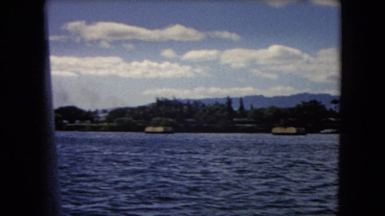 Harbor water and distant shoreline seen through dark boat-window framing.