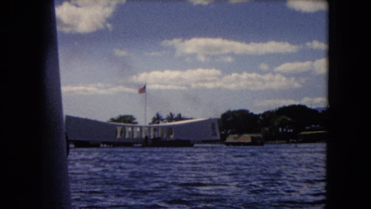 USS Arizona Memorial across harbor water with an American flag above it.
