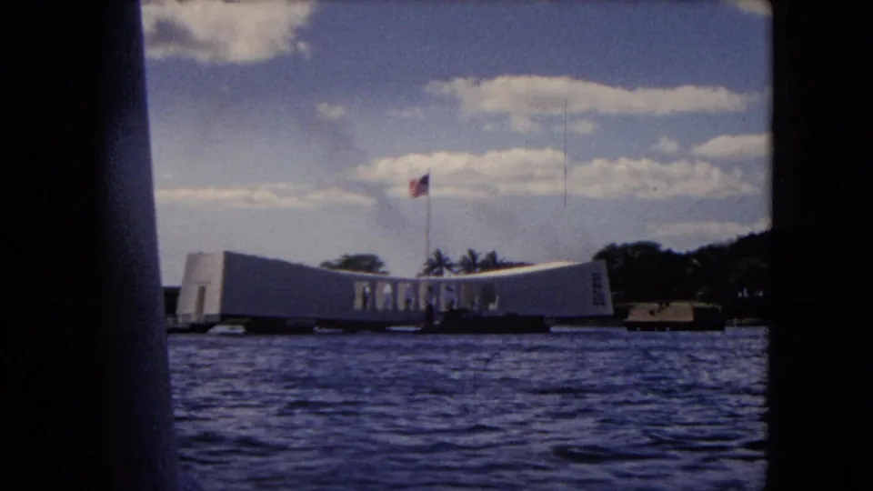 The USS Arizona Memorial remains in view from the boat, with the flagpole, shoreline trees, clouds, and film-frame borders visible.