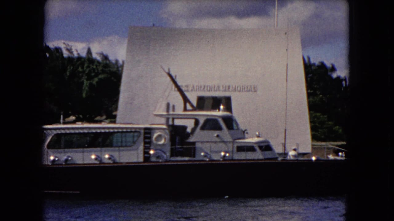 Close view of the USS Arizona Memorial with a tour boat alongside on harbor water.