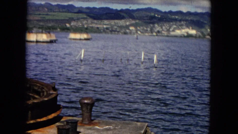 Harbor markers, a dock edge, and rippled water appear before the Honolulu shoreline and mountains in the final 1968 frame.