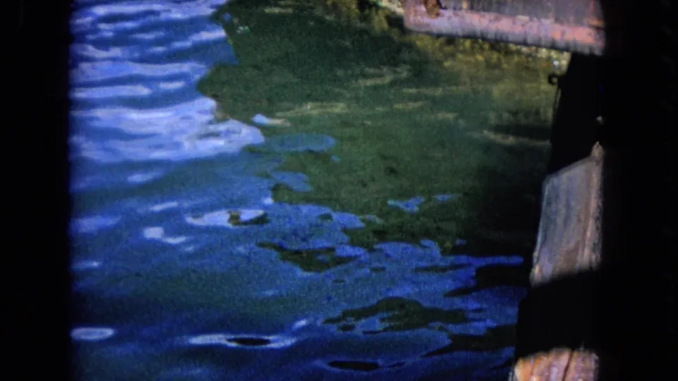 Blue water and green surface patches appear between dark dock structures in this Honolulu 8mm frame.