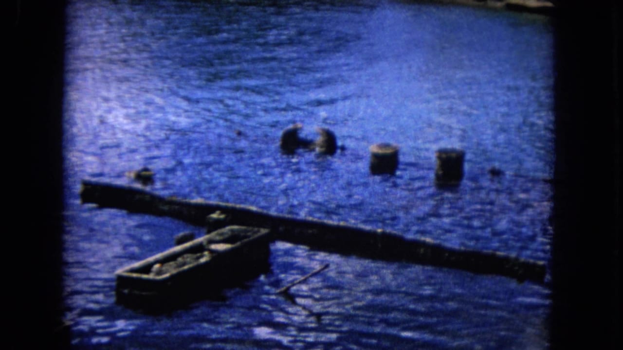 Weathered dock beam and small empty hulls floating in blue harbor water.