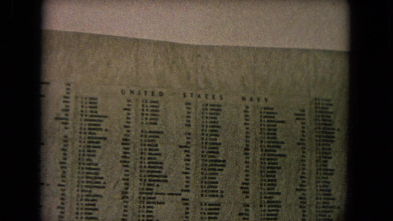 Engraved U.S. Navy names on a memorial wall seen through an 8mm film frame.