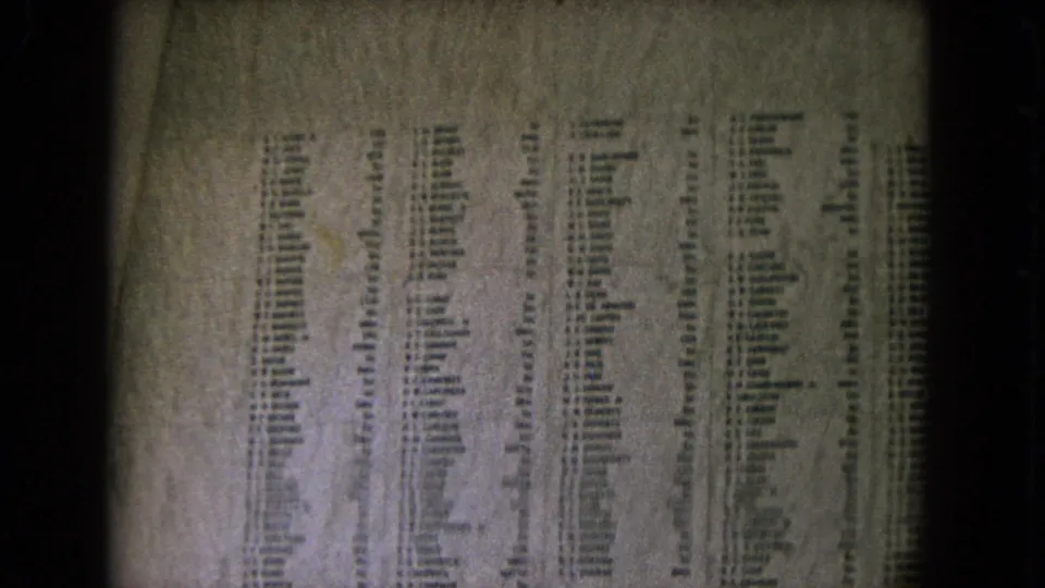 Grainy 8mm frame of engraved U.S. Navy names on the U.S.S. Arizona Memorial wall in Honolulu.