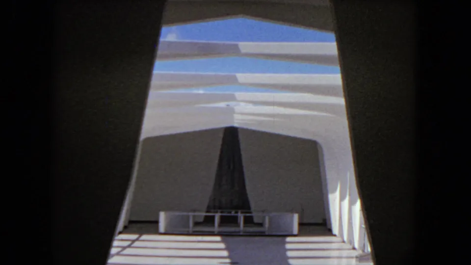 Final 1968 Honolulu frame with angled architectural lines, blue-tinted daylight, striped floor shadows, and a dark central structure.