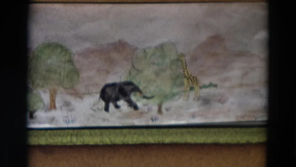1968 Lahaina Maui home-movie frame showing a handmade painted savanna backdrop with an elephant, giraffe, trees, and hills.
