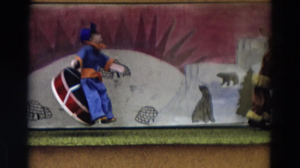 1968 Lahaina, Maui home-movie frame showing a puppet on a sled before painted igloos, polar bears, and snowy hills.