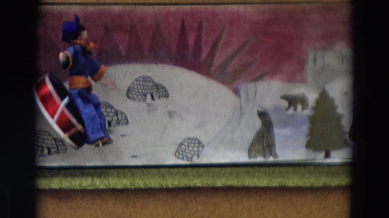 1968 Lahaina, Maui frame with the puppet and sled near painted igloos, a polar bear, snowbanks, and a tree.