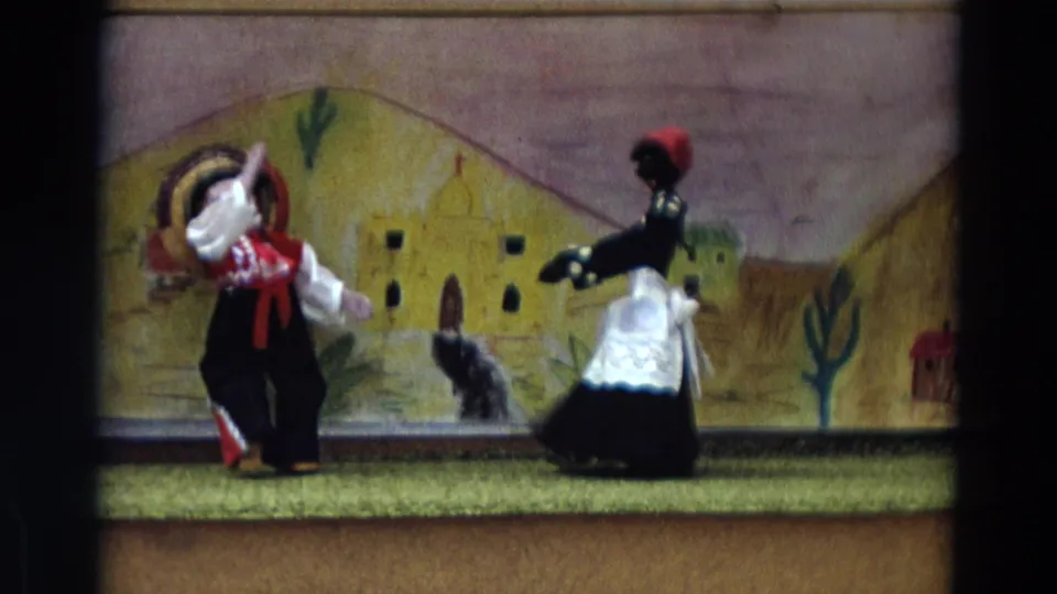 1968 Lahaina Maui 8mm frame showing a sombrero-wearing puppet and a dark-haired puppet in a white apron on the stage.
