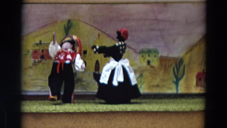 The puppet dolls appear closer together on the small stage, with painted buildings and cactus forms behind them.