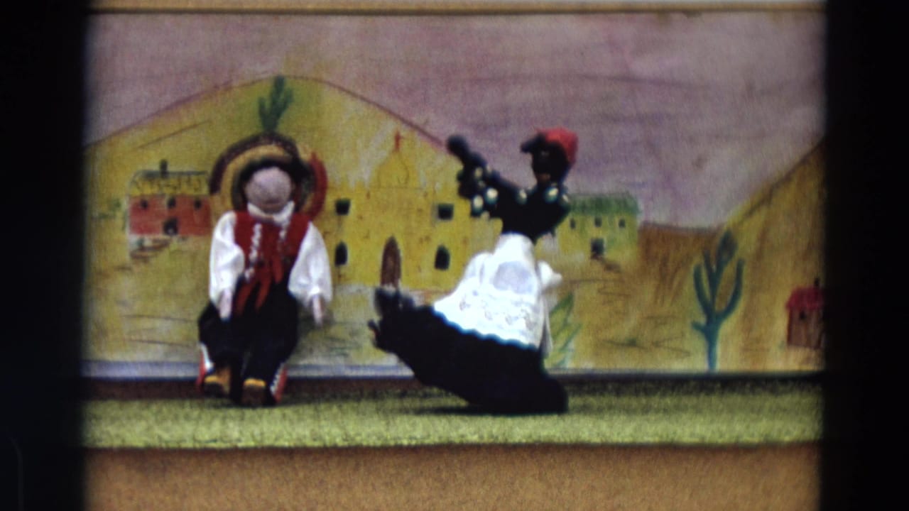 Two dressed puppets perform on a small stage before a painted village backdrop.