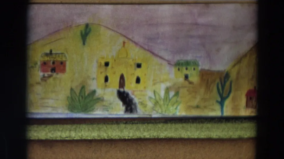 1968 8mm frame showing a small black dog figure alone against a hand-painted village backdrop.