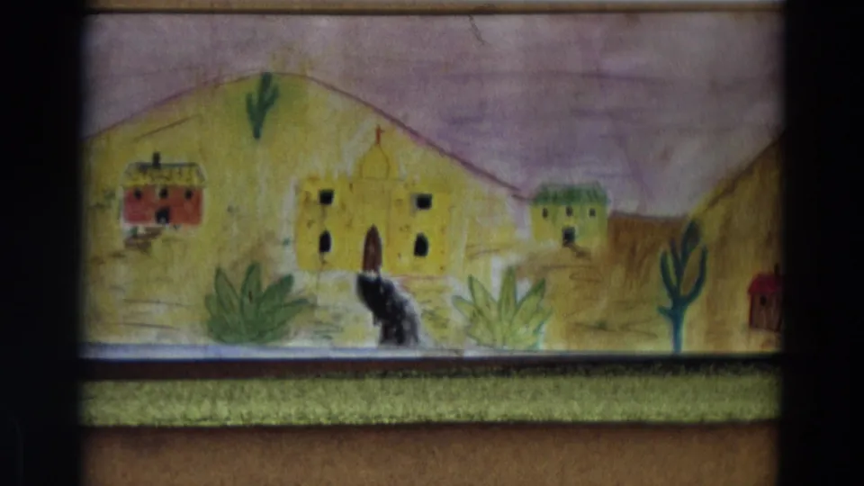 1968 Lahaina, Maui home-movie frame showing a handmade village backdrop with small buildings, desert plants, hills, and a dark figure in front.