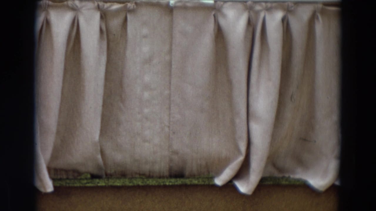 Close view of beige pleated curtains hanging across a small stage area.
