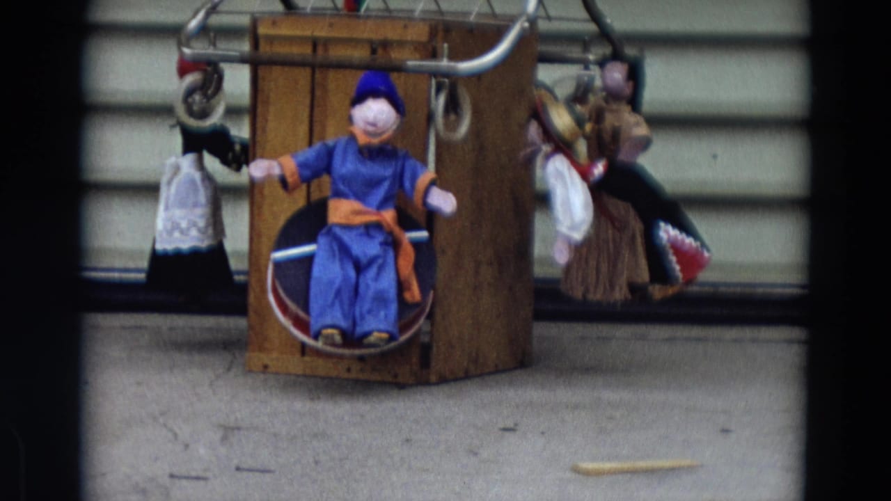 Handmade puppets arranged around a wooden box on a concrete floor.