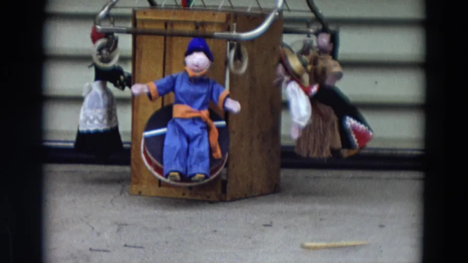 1968 Lahaina, Maui home-movie frame showing handmade puppets, including a central seated figure in blue and orange.