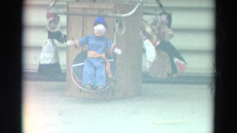 Faded 8mm frame from Lahaina, Maui in 1968 showing a wooden puppet display washed by bright exposure.