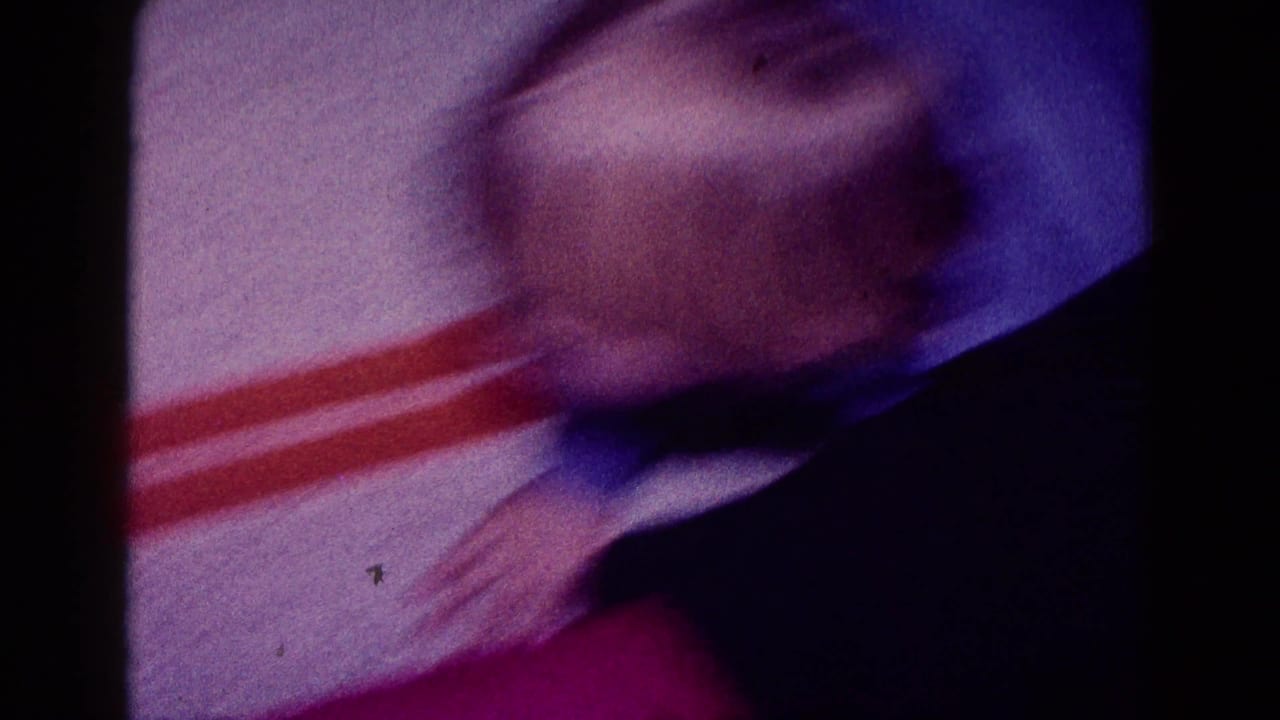 Soft, blurred 1968 Minnesota home-movie frame showing red plastic toy track on carpet during indoor play.
