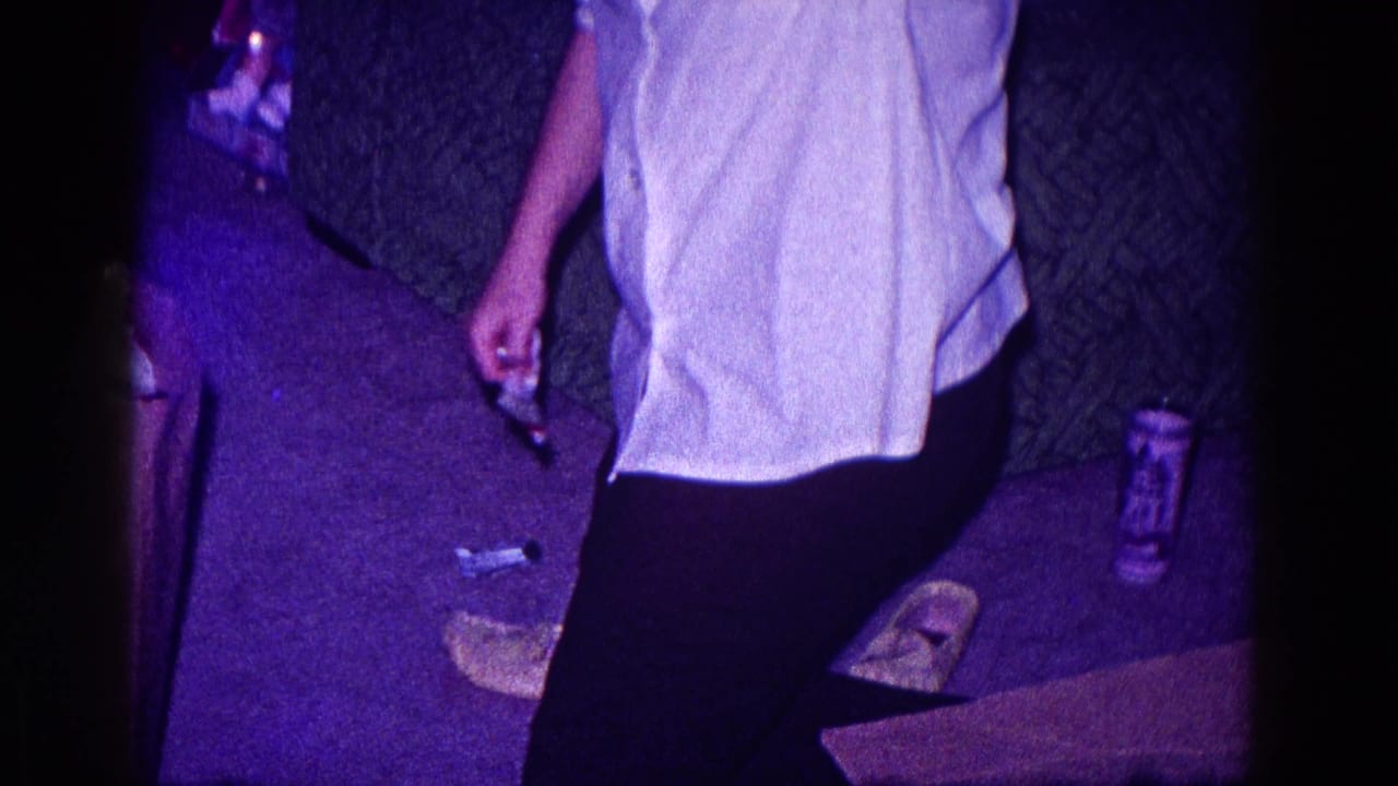 A woman in a light shirt and dark pants stands near fabric scraps and small tools in a dim 1968 Minnesota interior.