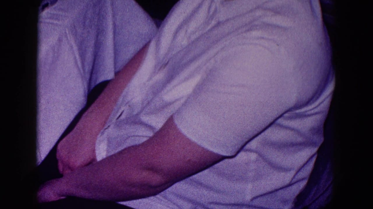 Close cropped view of a seated person in a white shirt with arms folded.