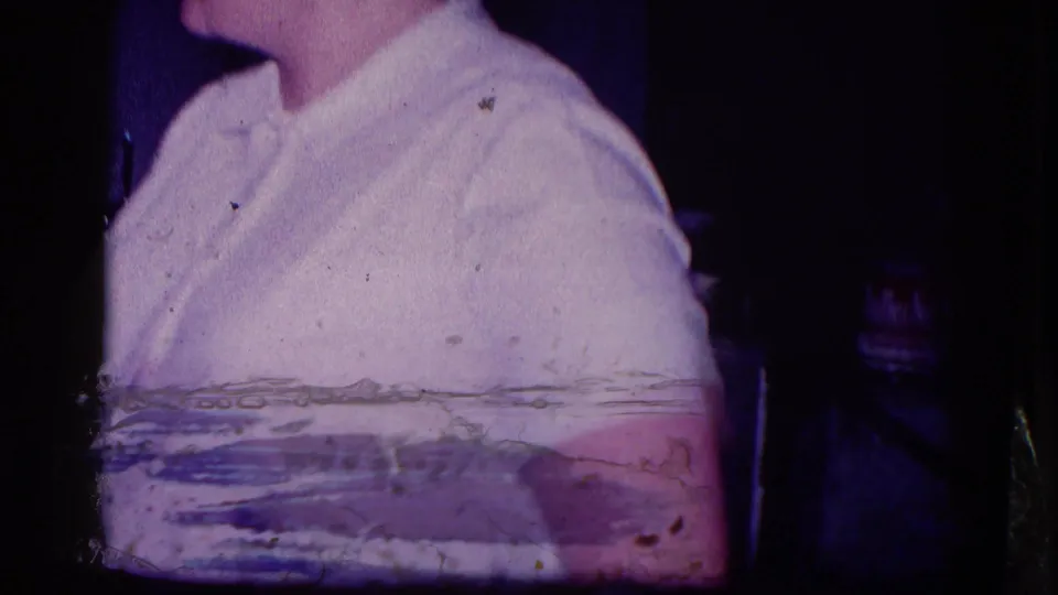 A partial adult figure in light clothing appears at the edge of a 1968 Minnesota home-movie frame, with film wear and dark borders visible.