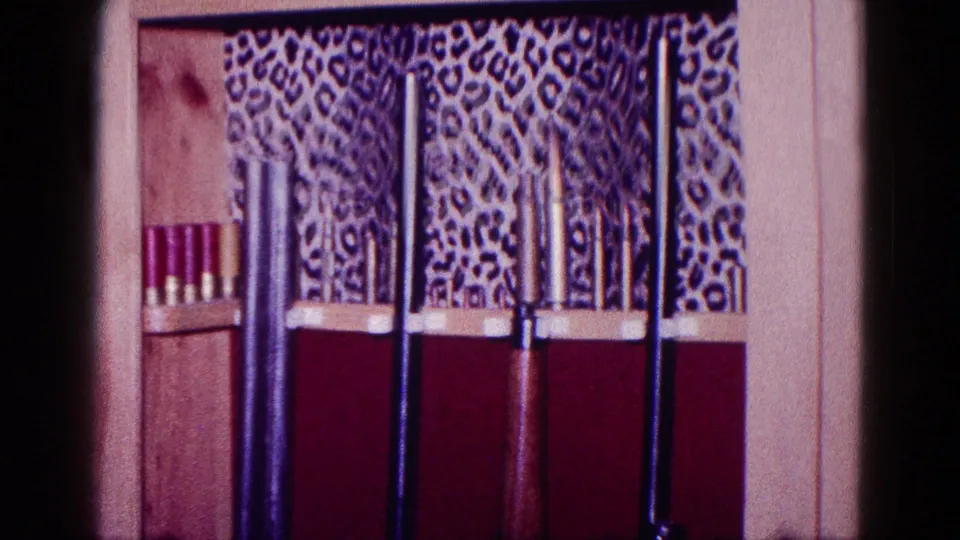 1968 Minnesota 8mm frame showing long guns and shotgun shells in a wooden display case with patterned backing.