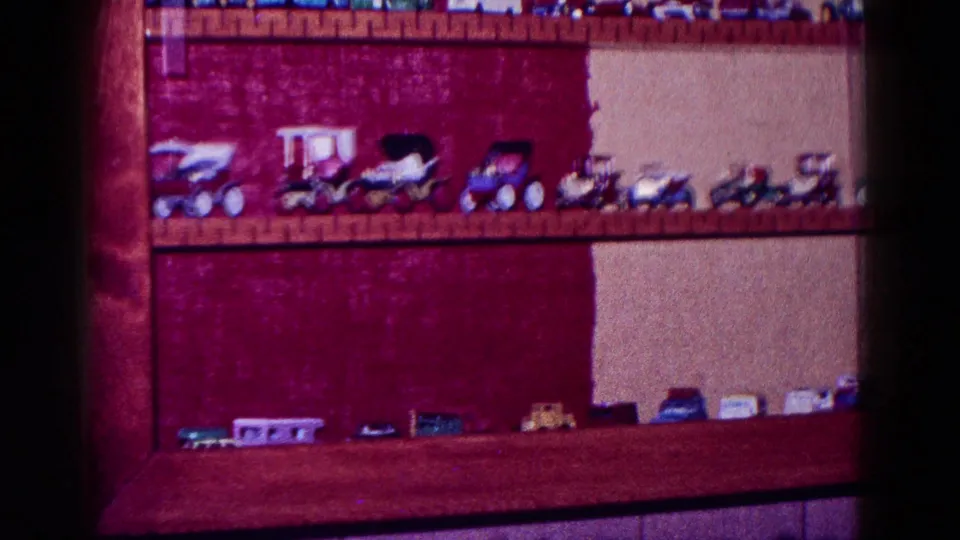 1968 Minnesota 8mm still showing larger toy trucks and small cars arranged on shelves in a private interior.