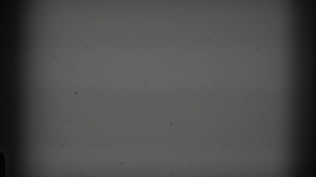 Mostly dark, underexposed frame with film grain and a faint vertical edge.