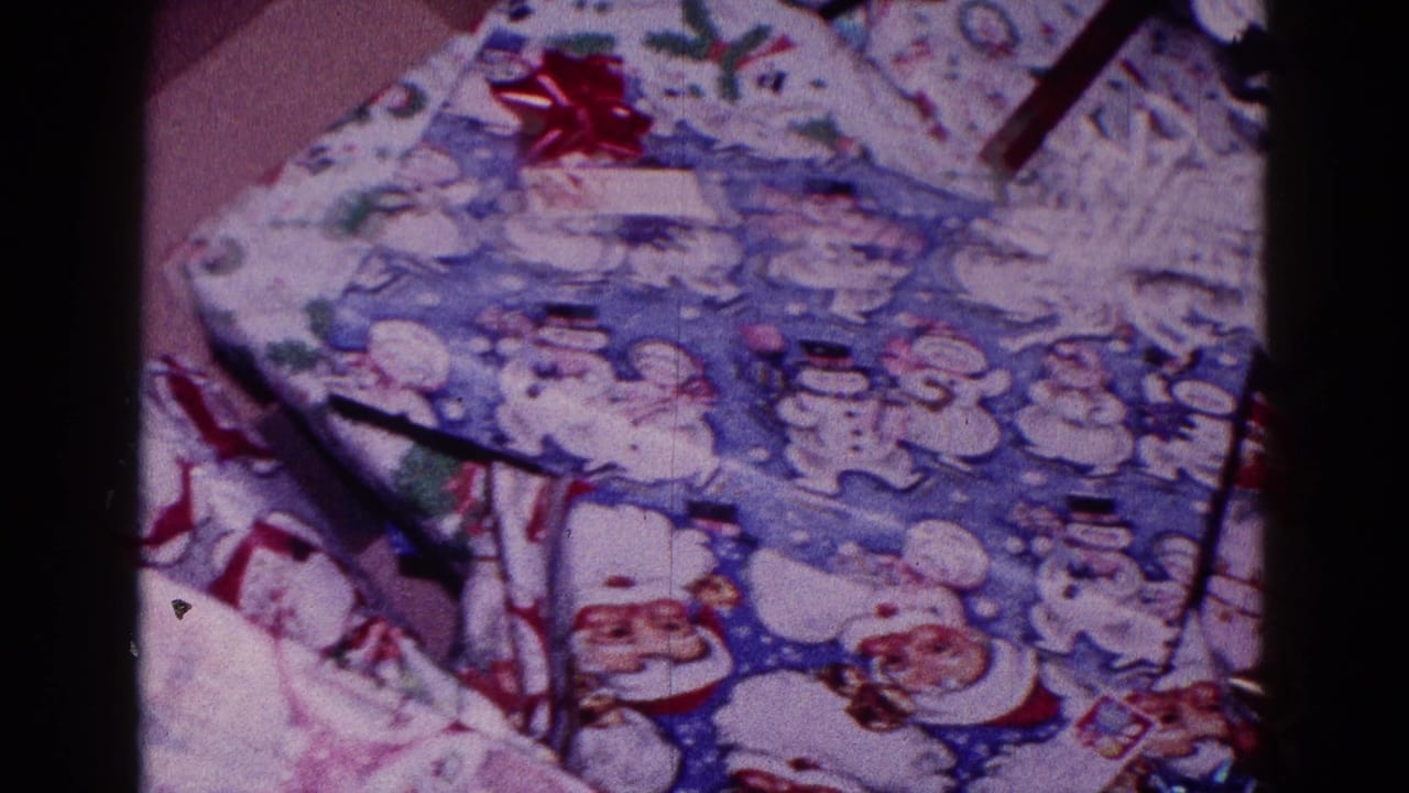 Wrapped Christmas presents with Santa and snowman paper on an indoor floor.