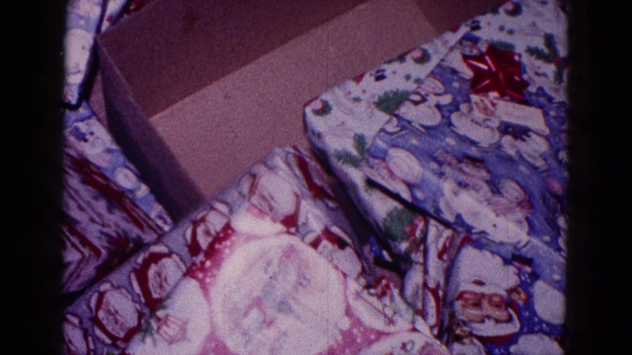 Open cardboard box beside wrapped Christmas gifts and patterned holiday paper.