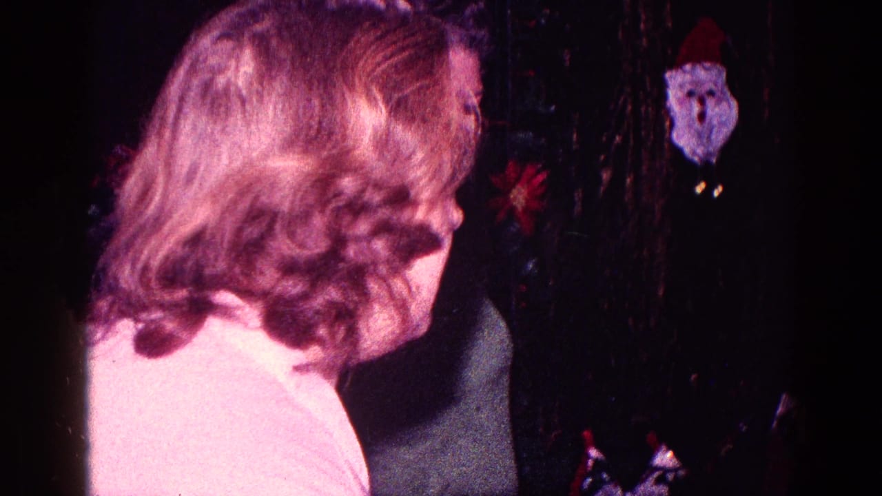 1968 Minnesota home-movie frame showing a woman near a decorated Christmas tree with a small Santa ornament visible.